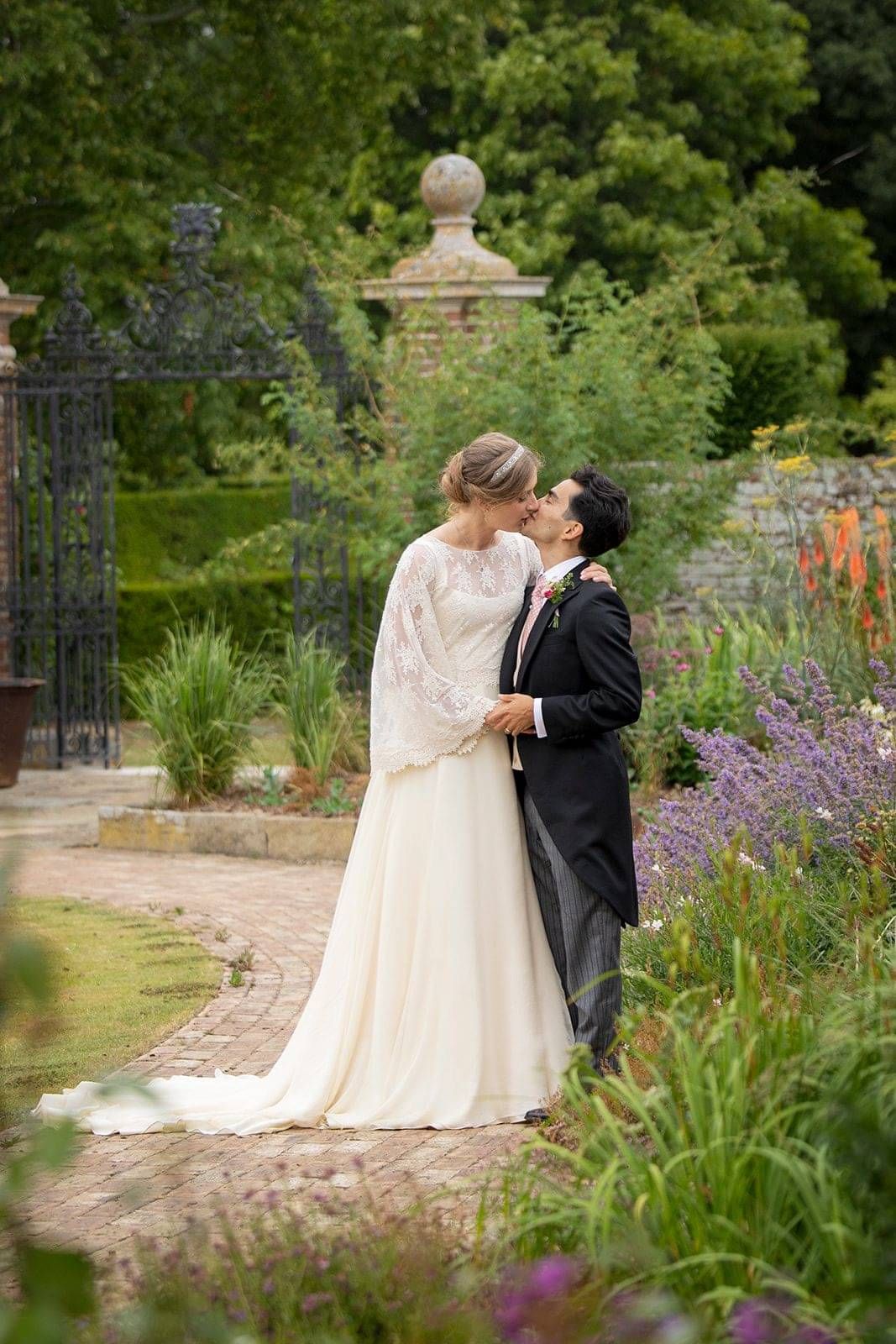 Bride and groom kiss on the grounds at Hole park gardens, Bride wearing custom made wedding dress by Kate Edmondson