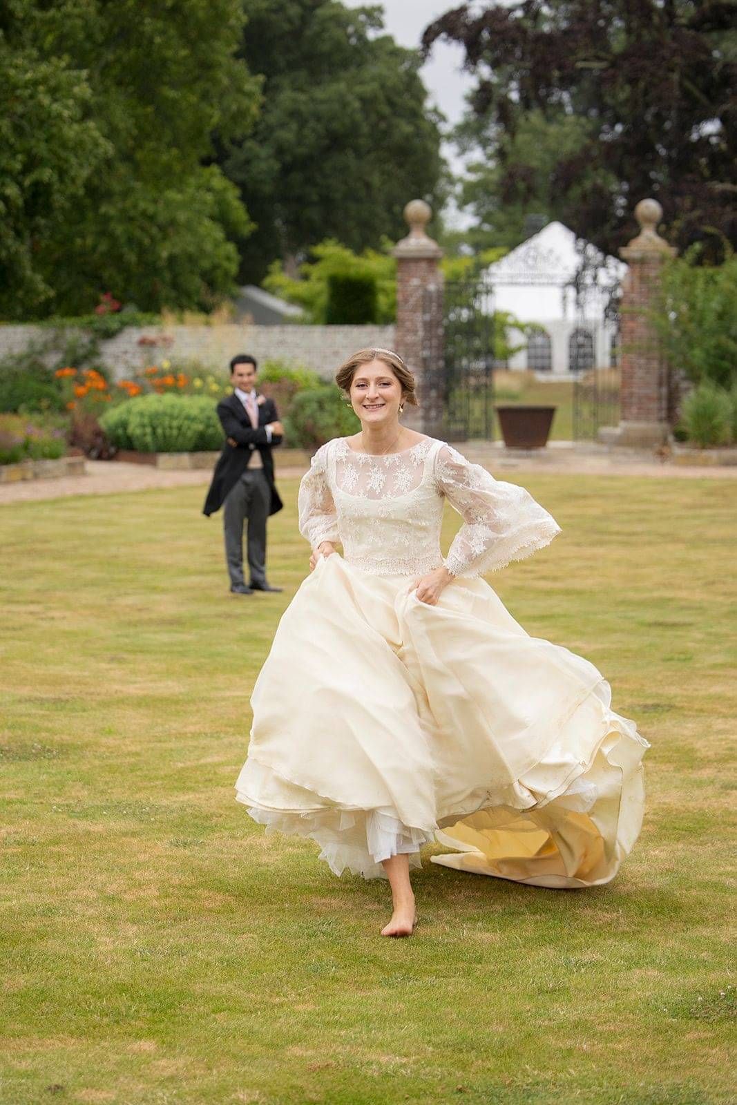 Bride having a playful run on her wedding day at Hole Park Gardens wearing bespoke wedding dress and lace bridal top