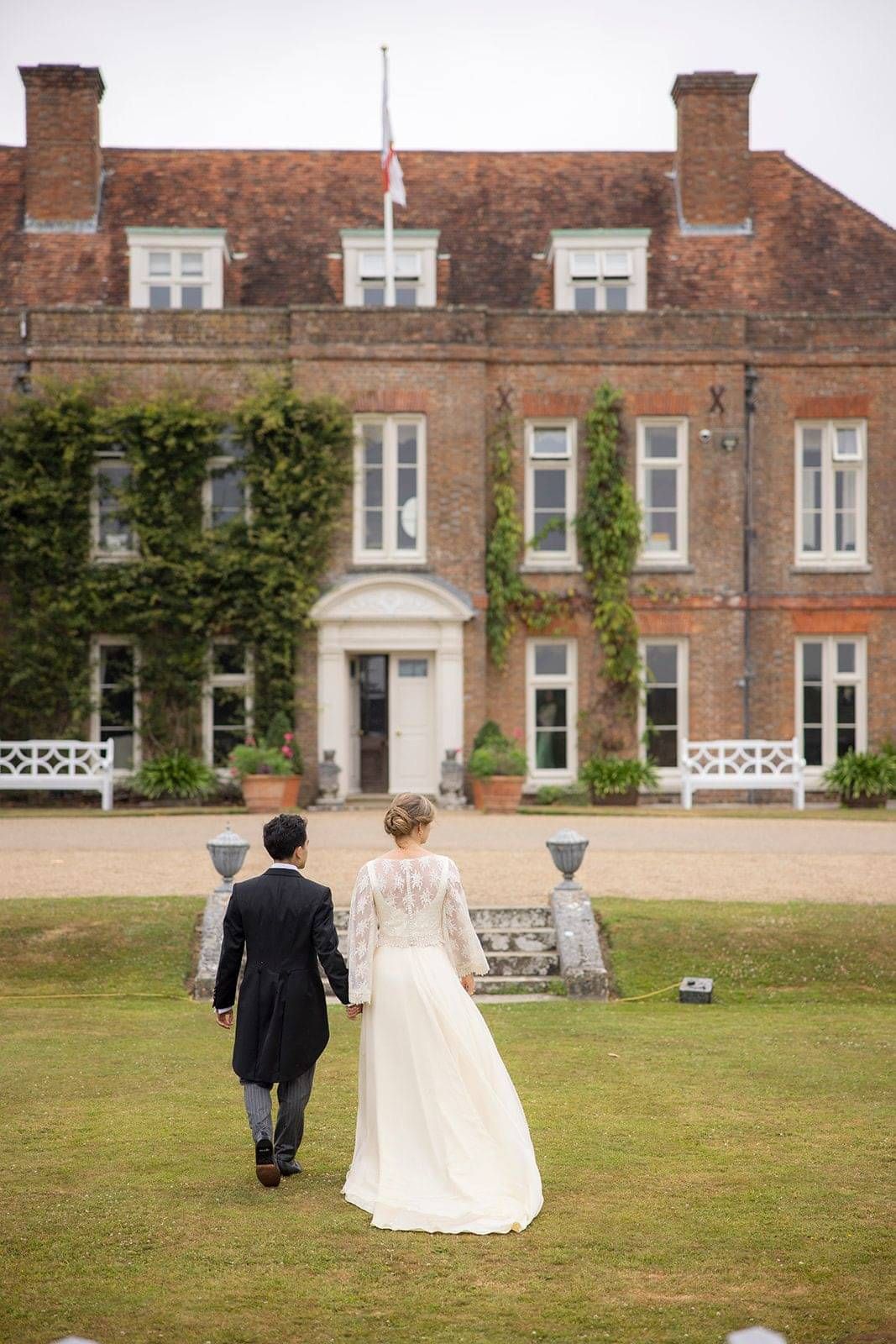 Back profile of bride & groom bride wearing a bespoke custom wedding dress design by Kate Edmondson, Wedding at Hole Park Gardens