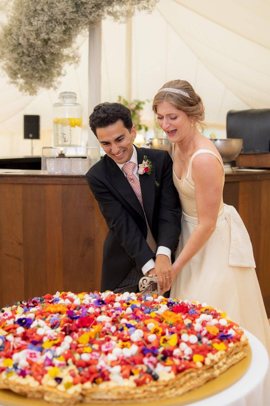 Bride and groom cutting the cake, bride wearing custom made wedding dress by Kate Edmondson