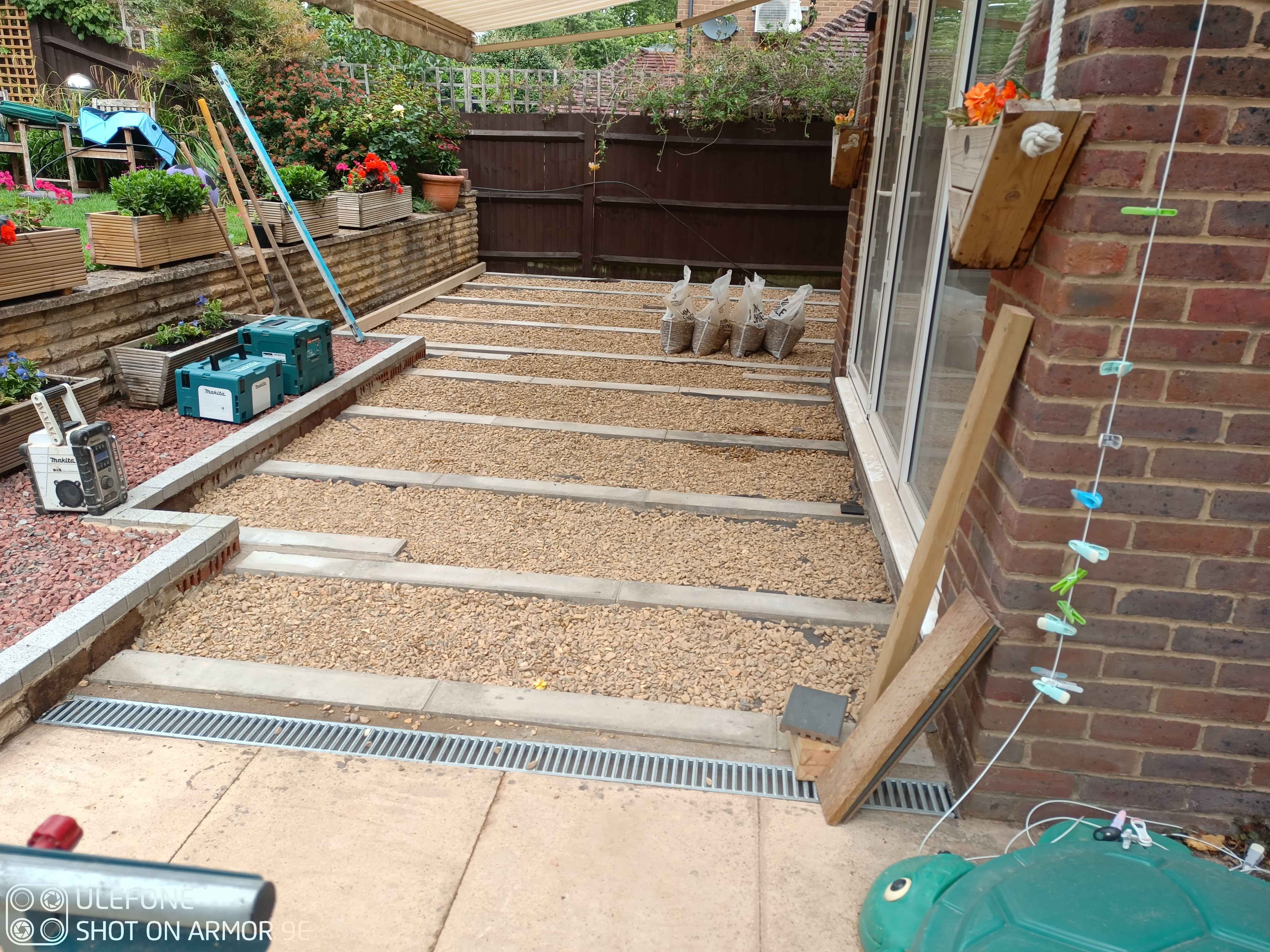 Image shows the prepared base with all the pads in and level, the repaired wall and the gravel infil.