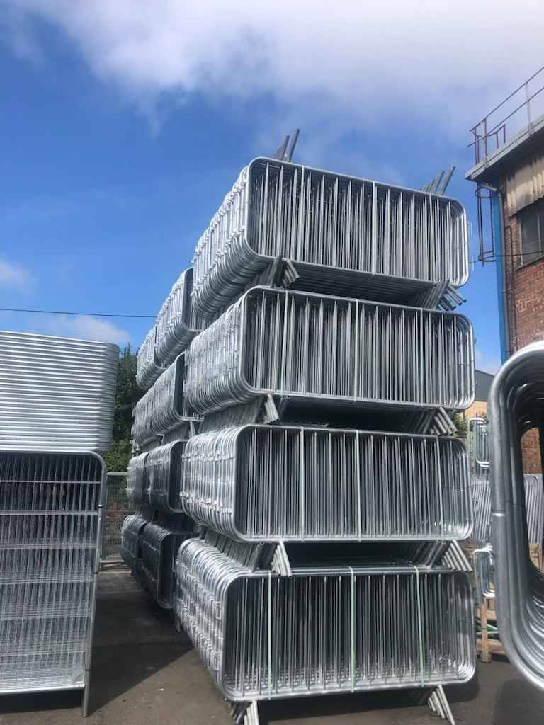 Tall stacks of galvanised crowd control barriers at Tempfence UK ready for bulk supply and fast UK-wide transport
